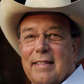 A man with glasses wearing a cowboy hat.