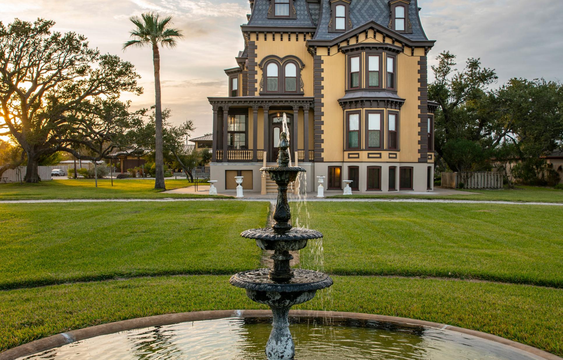 Fountain in front of mansion during sunset