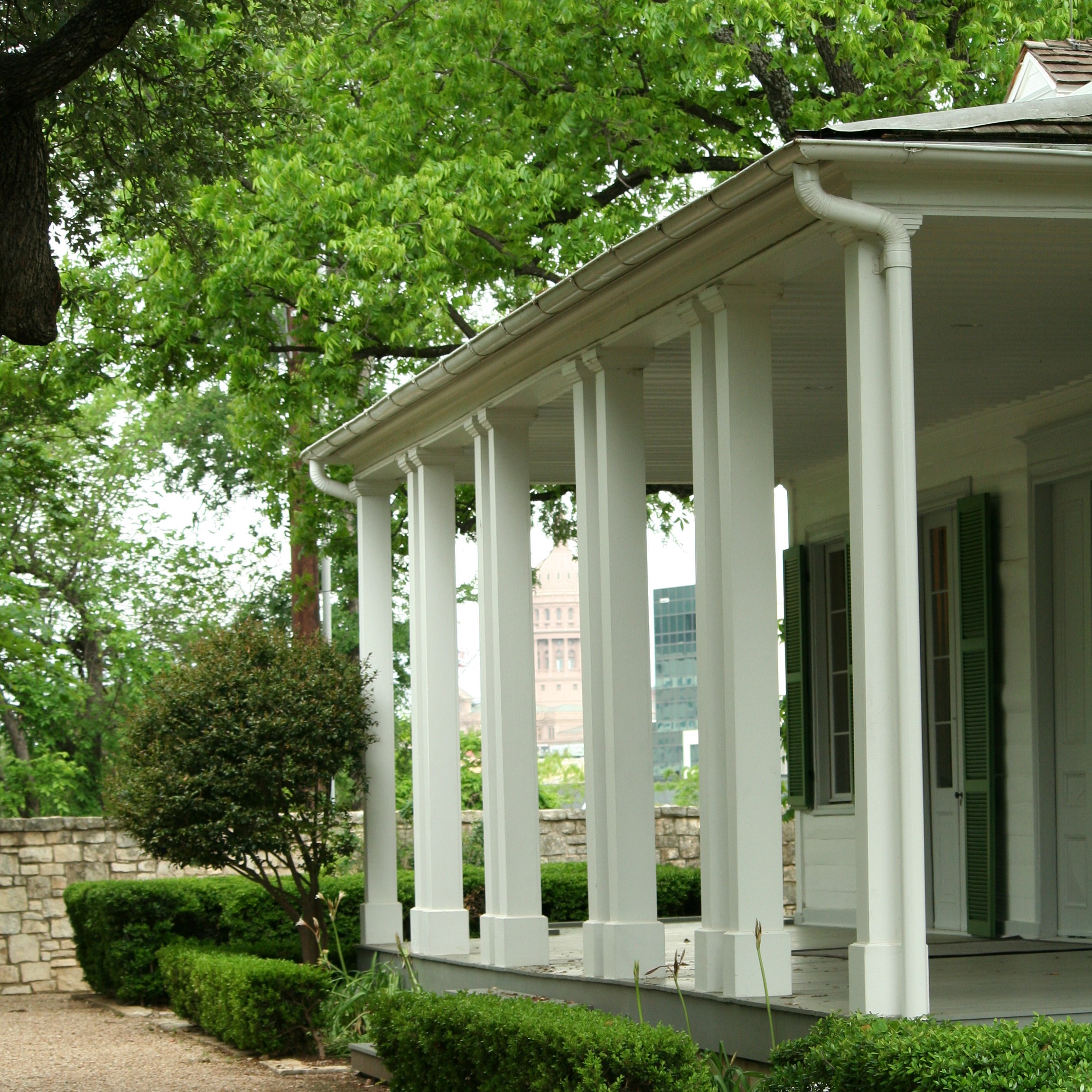 Corner view of the white columns at the French Legation with trees in the background
