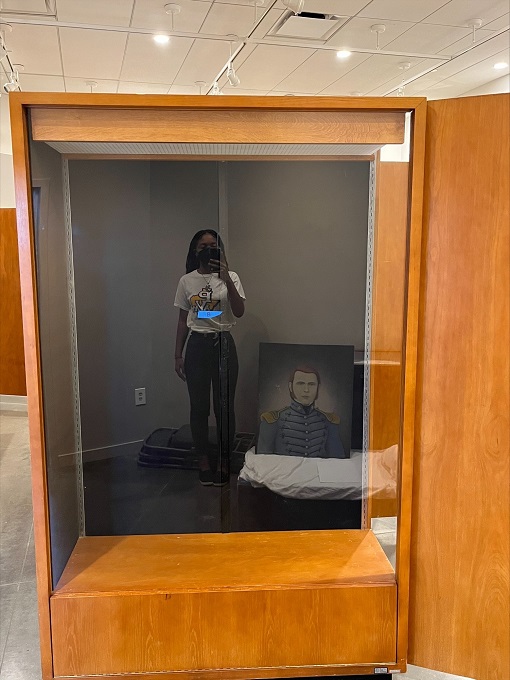 Reflection of a young woman in the glass of a tall museum exhibit case