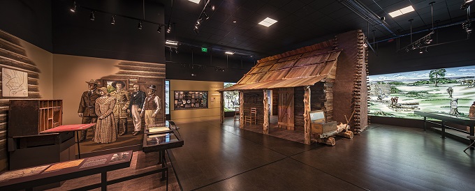 Log cabin inside a museum with exhibits on either side
