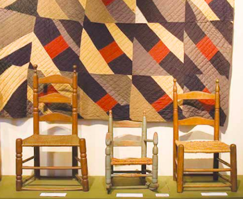Homespun quilt and three wooden chairs in a museum