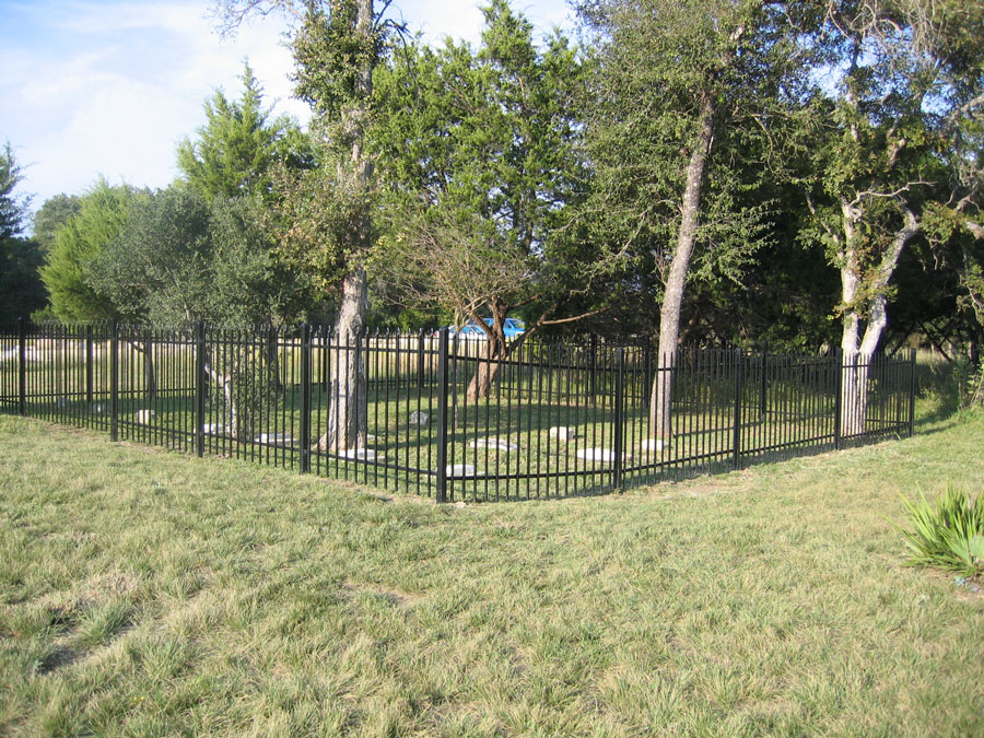 A photo of a fenced-in family cemetery in a field surrounded by trees