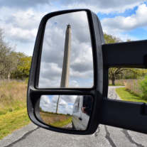 Side view mirror of a van with the San Jacinto Monument in the reflection