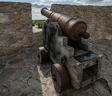 A brown metal cannon atop the Presidio La Bahia